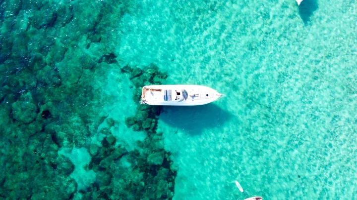 Three luxury yachts at anchor in green sea in daylight